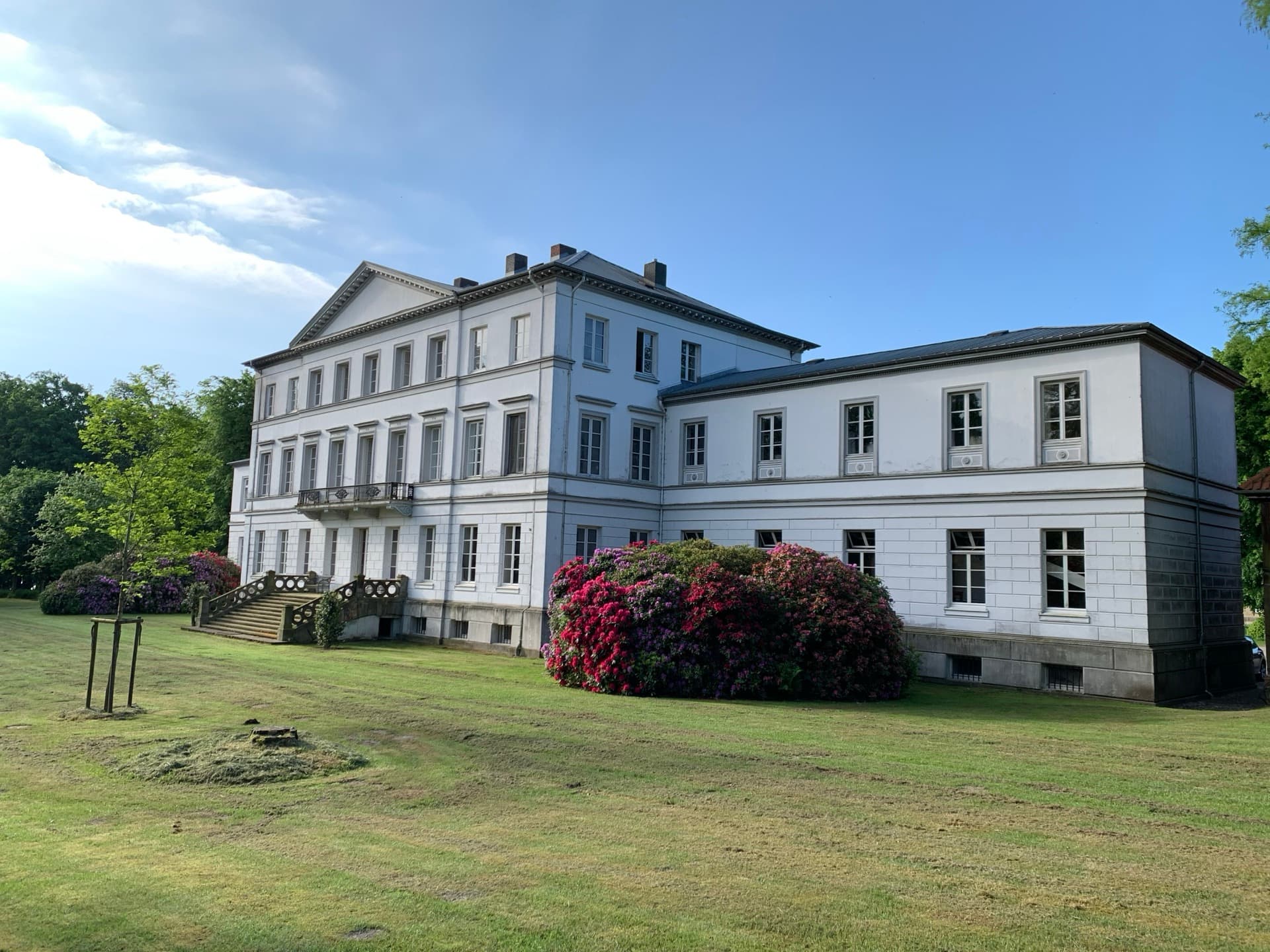 Gutshaus Nehmten — klassizistisches Herrenhaus mit Treppenaufgang und blühendem Rhododendron